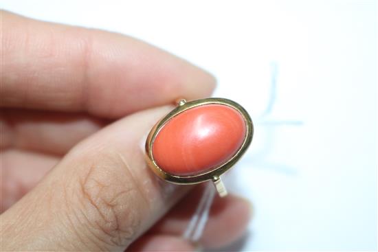 A yellow metal and oval cabochon coral ring, size R.